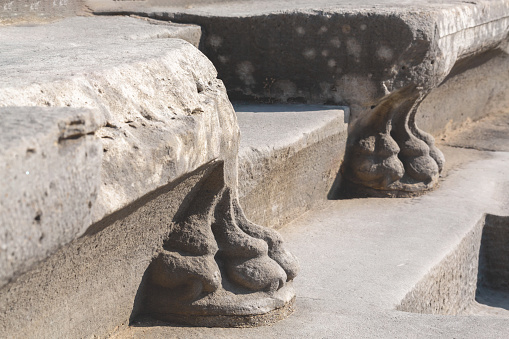 Side ancient theater. Carved stone seat supports in form of lion claws, shadows accentuate ancient craft. Side, Antalya, Turkey (Turkiye)
