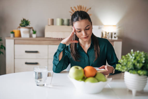 istock A young beautiful woman is sitting at a table and reading a book. 2084765606