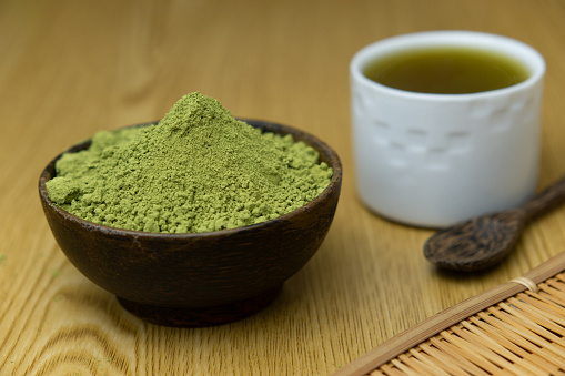 Close-up pictures of hot tea, green tea with Matcha tea powder, small cups on a wooden table.