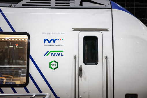 Cologne, Germany - November 7, 2022: Picture of a sign with the logos of VRR, NWL, NVR on one of their suburban trains in Cologne train station. Nahverkehr Rheinland (NVR): It is an organization involved in organizing regional rail passenger transport (SPNV) in North Rhine-Westphalia. NVR is one of the partners implementing the Rhine-Ruhr Express (RRX) project, which is a high-performance mobility service offering innovative and digitally networked trains for the Rhine-Ruhr region. Nahverkehr Westfalen-Lippe (NWL): This organization manages the regional rail transport for Westphalia-Lippe and is the second-largest purchaser of SPNV services in North Rhine-Westphalia. NWL covers an extensive area serving about 5.6 million residents with a network of almost 2,000 kilometers of rail. Verkehrsverbund Rhein-Ruhr (VRR): VRR is the local public transport authority for the Rhine-Ruhr metropolitan region, which is one of the largest metropolitan areas in Europe. It coordinates and finances the regional passenger rail services in the region.