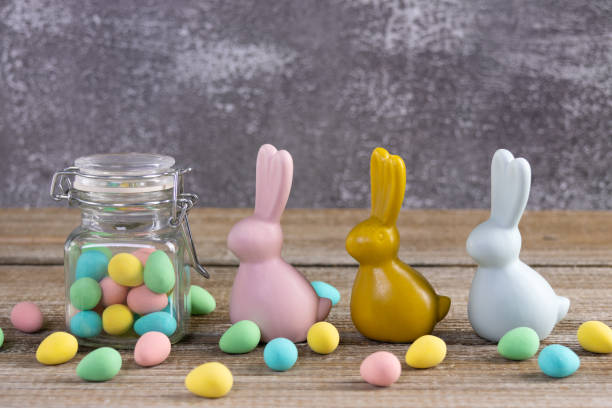 istock Easter composition with three bunnies and a jar with colorful candies. 2084837722