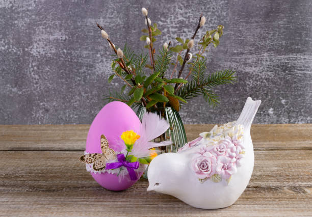 Easter decorated egg, pussywillow and a figurine of bird on the table.