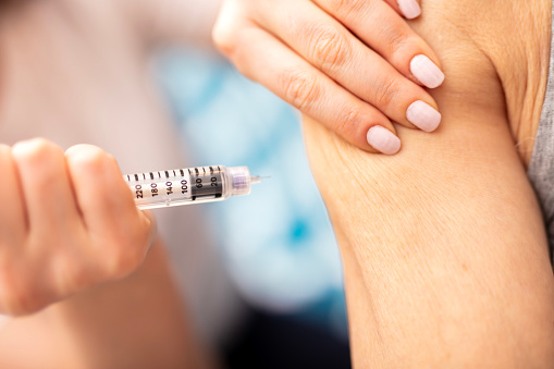 woman is injecting insulin in senior arm