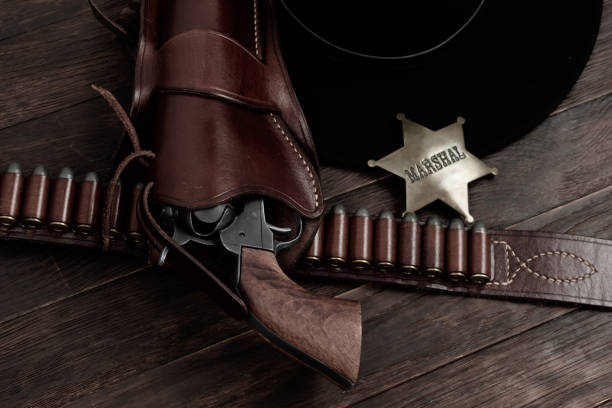istock Marshal star with gun, holster and gun belt with old west hat on table. Top view. 2084874535