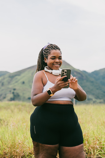 Plus size woman using smartphone on walk outdoors