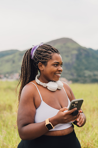 Plus size woman using smartphone on walk outdoors