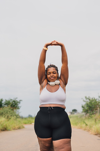 Plus size woman stretching outdoors