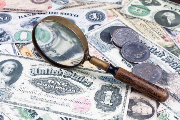 istock Old west period US banknotes and silver certificates with silver dollar coins and magnifying glass 2084882208