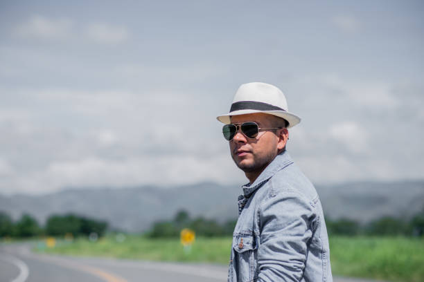 man wearing a cap and goggles while walking down a main street in the open air