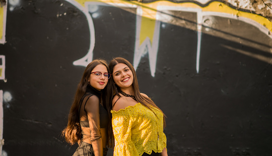 portrait of two young women in the city as they smile and share time of friendship.