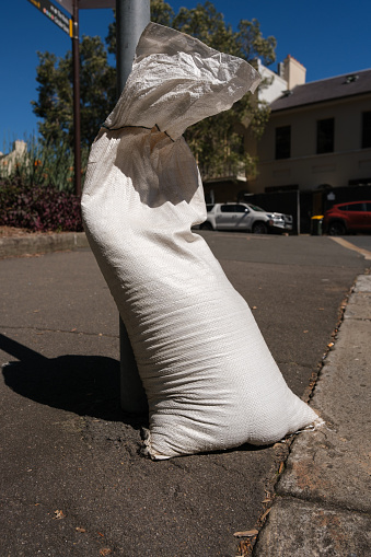 Close-up on a discarded sandbag by the side of a road on a sunny morning.
