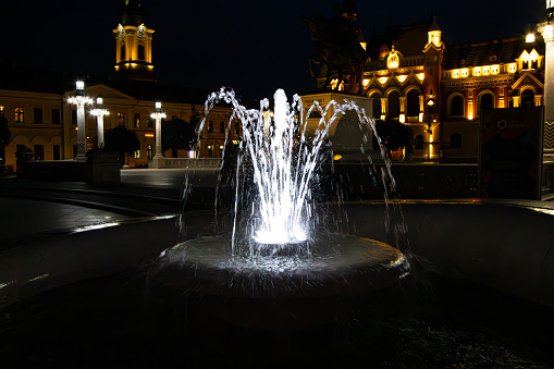 Oradea, Romania. July, 13, 2023. Decorative water fountain at night in the Union Square in Oradea city, Romania