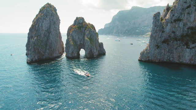 Capri sea stacks create a stunning gateway in the Tyrrhenian Sea. Aerial view of world famous Faraglioni cliffs in summertime.