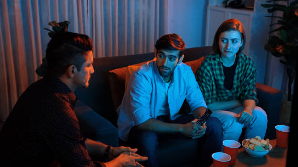 istock Father and mother watching movie while eating snack with friend. Convocation. 2084956136