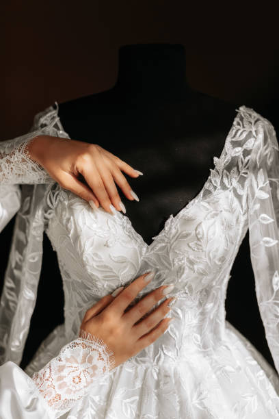 white wedding dress with long train in room with home interior. the hands of the bride are on the dress with a large pattern - wedding bride buying caucasian photos et images de collection