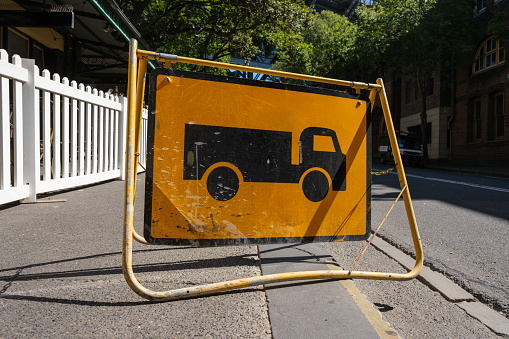 A temporary yellow metal roadsign with a truck icon indicating heavy trucks are in the area.