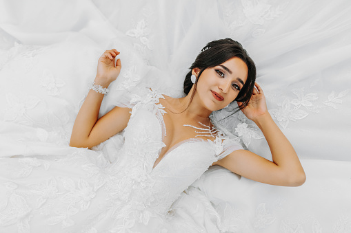 young beautiful bride in a wedding dress lying down, fashion. The photo is taken from above. Near the wedding dress. A dreamy bride is enjoying her wedding