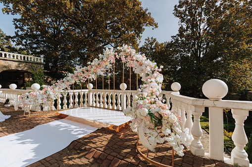 Modern ceremony in European style. Wedding arch with roses on the background of the forest. Jewelry made of fresh flowers, flowers and crystals. Front view.