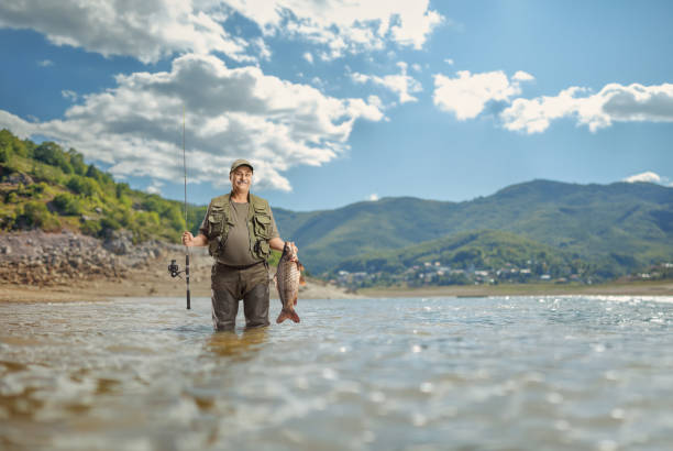 istock Fisherman in a uniform standing inside a mountain lake 2084979831