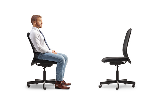 Profile shot of a businessman sitting in an office chair opposite an empty chair isolated on white background