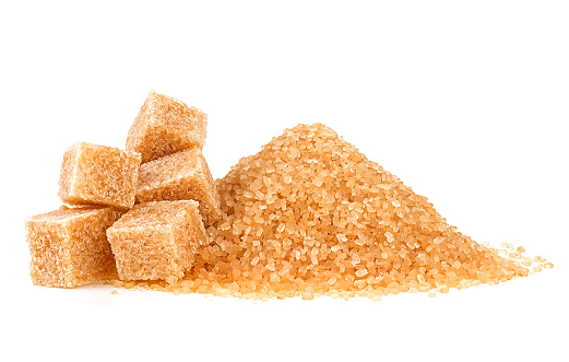 Pile of brown granulated sugar and sugar cubes isolated on a white background. Unrefined brown cane sugar pile.