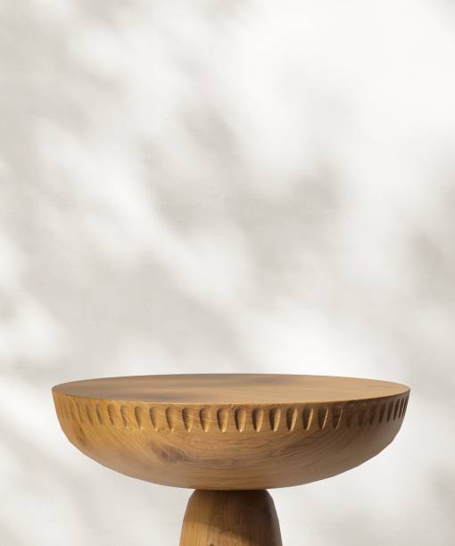 istock Round wooden pedestal table podium in dappled sunlight, leaf foliage shadow on white wall 2085007594