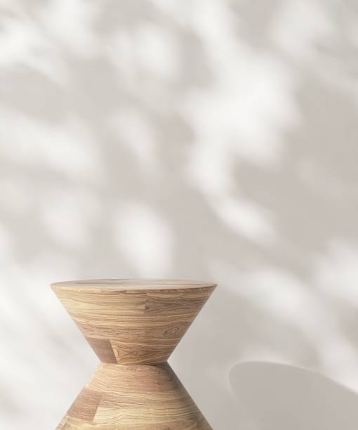 istock Round wooden pedestal table podium in dappled sunlight, leaf foliage shadow on white wall 2085012679