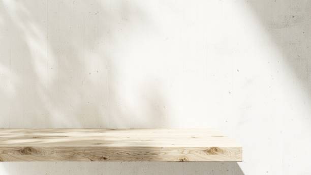 istock Brown natural wooden shelf in sunlight, tropical tree leaf shadow on white concrete wall 2085013212