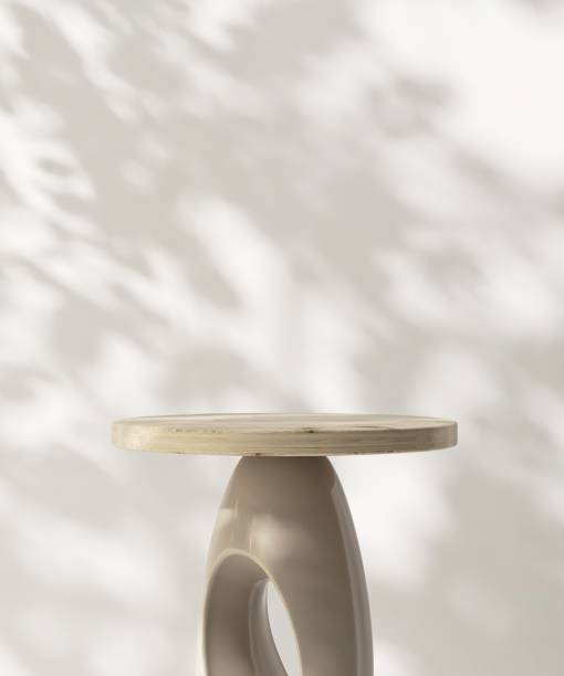 istock Round wooden pedestal table podium in dappled sunlight, leaf foliage shadow on white wall 2085014762