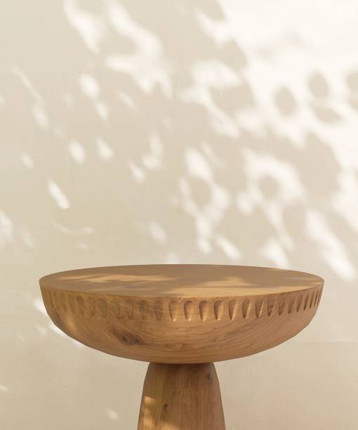 istock Empty brown round wooden table podium in dappled sunlight, leaf foliage shadow on white cream concrete wall 2085044075