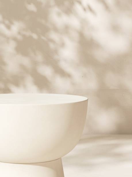 istock Empty white stone table podium in dappled sunlight, leaf foliage shadow on white cream concrete wall 2085044081