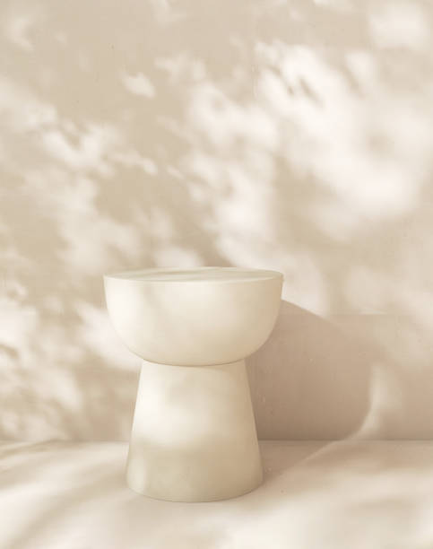 istock Empty white stone table podium in dappled sunlight, leaf foliage shadow on white cream concrete wall 2085044084