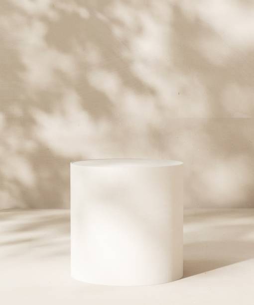 istock Empty white stone table podium in dappled sunlight, leaf foliage shadow on white cream concrete wall 2085044591