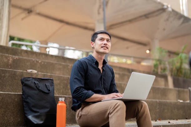 istock Asian businessman with reusable eco friendly ecological cup using laptop and sitting outside the office building. Eco friendly, sustainable lifestyle concept 2085069140