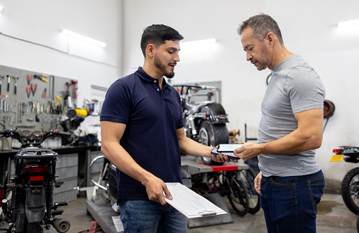 Latin American man making a contactless payment at a motorcycle garage