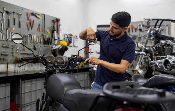 Mechanic cleaning the side view mirror of a motorcycle at a garage Latin American mechanic cleaning the side view mirror of a motorcycle at a garage broken side view mirror stock pictures, royalty-free photos & images