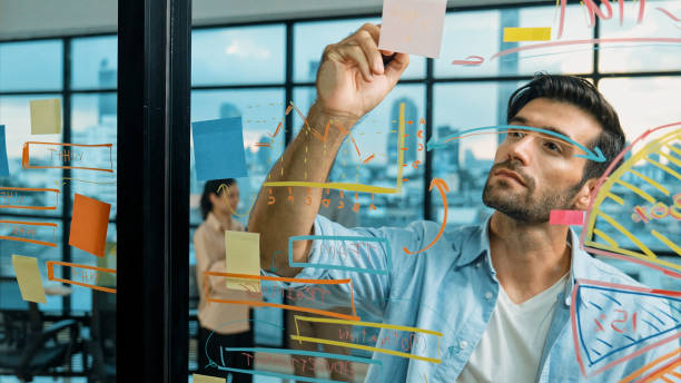 istock Businessman uses sticky notes at glass wall to brainstorming idea. Tracery 2085135621