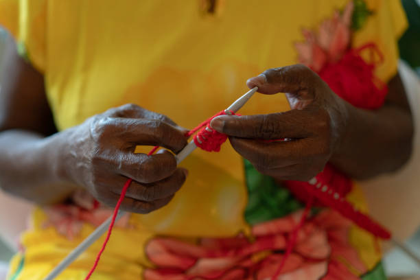 Black senior woman knitting red wool