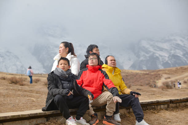 Amidst the beautiful alpine landscape, a family takes a break on a ski lift, their colorful outfits standing out against the pristine snow
