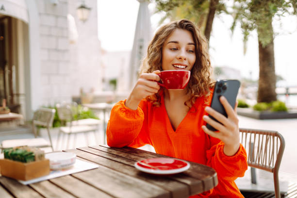 istock Young woman at summer cafe drinking coffee and using mobile phone. 2085244338