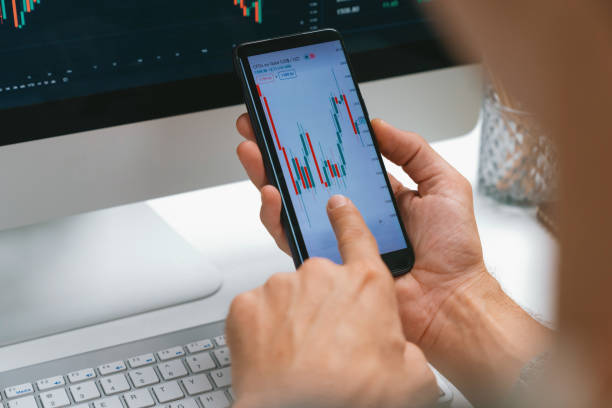 istock Investors pointing on screen with smartphone with laptop in stock. Pecuniary. 2085246685