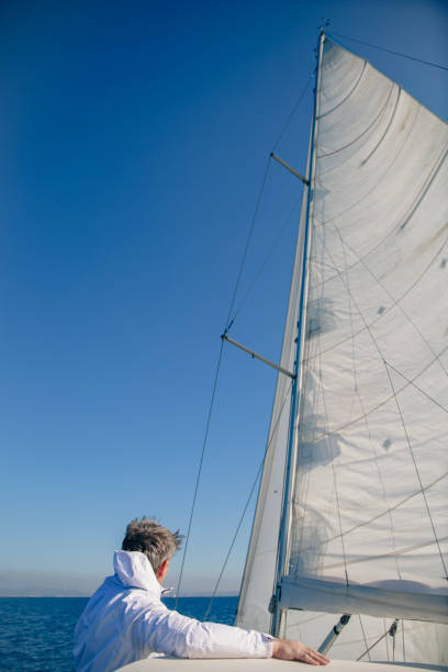 Young man steers sailboat on sea