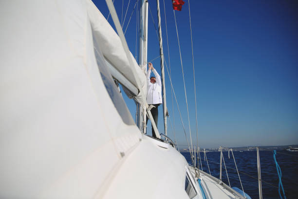 Young man steers sailboat on sea