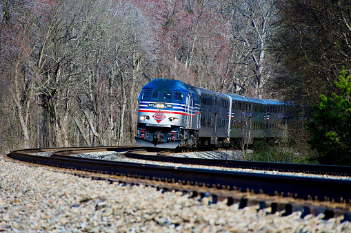 Fairfax Station, Virginia, USA - March 14, 2024: A Virginia Railway Express (VRE) commuter train travels on a curve heading Westbound on a sunny afternoon.