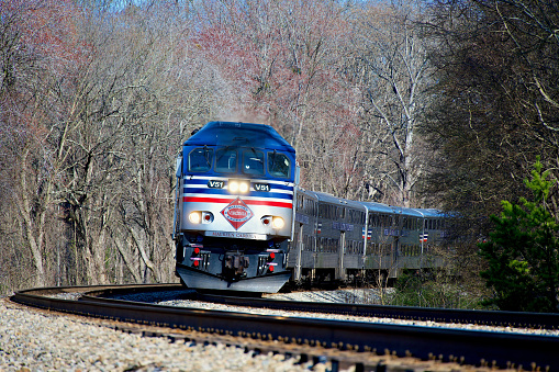 Fairfax Station, Virginia, USA - March 14, 2024: A Virginia Railway Express (VRE) commuter train travels on a curve heading Westbound on a sunny afternoon.