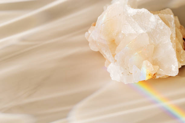 istock Quartz clear stone with Rainbow Beam at sunlight, bright sun glare and flare, beige blur background. Shiny magic crystal make caustic and light effects at sunshine, harmony and beauty of nature 2085336815
