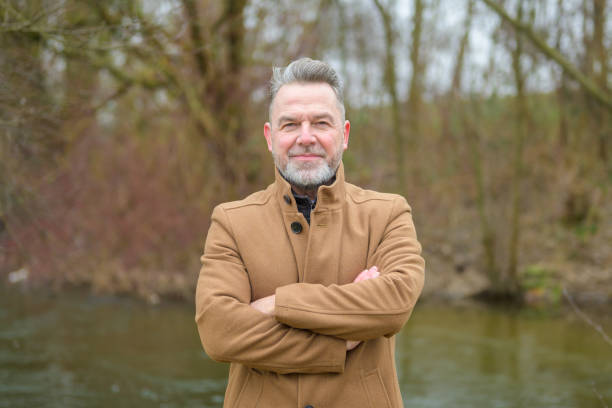 istock Middle aged man in a park in winter or spring with his arms crossed 2085339846