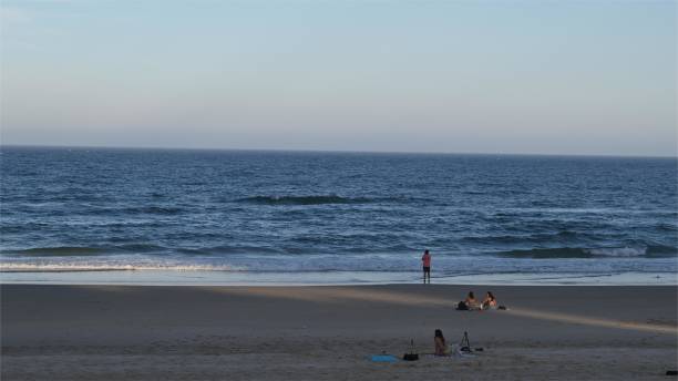 istock an empty beach at sunset with many people in the water 2085360632
