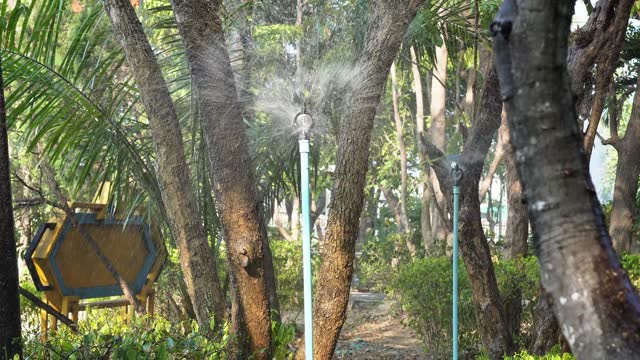 Video footage of water sprinklers spraying water in a public exercise park, Chiang Mai, Thailand.