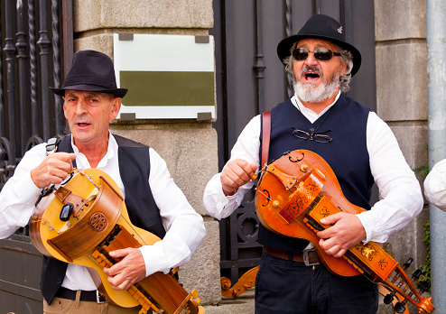 Senior men standing, playing the hurdy gurdy. Lugo city, Galicia, Spain during San Froilán autumn traditional celebrations.